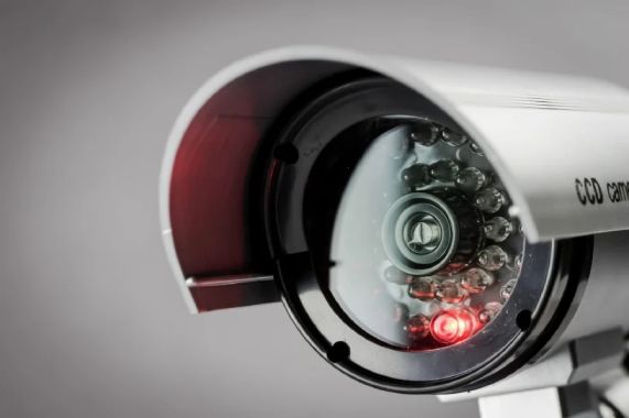 Prim-plan al unei camere de securitate IP cu lumina rosie aprinsa, evidentiind detalii tehnice si design modern.