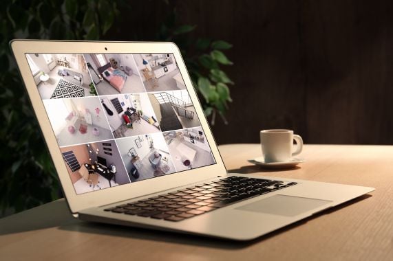Laptop pe o masa, afisand diverse imagini de pe o camera de supraveghere cu lumina.