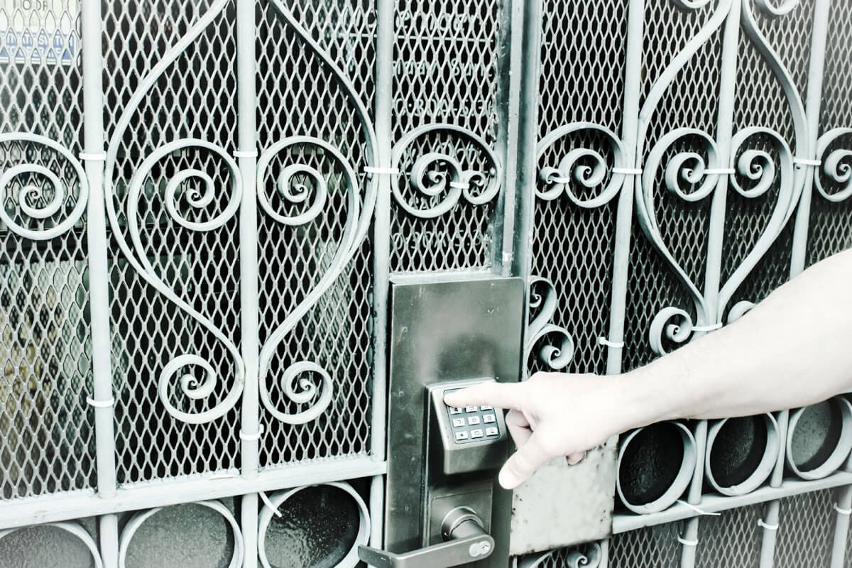 O persoana acceseaza o poartă metalica cu fotocelule, pregatindu-se sa intre.