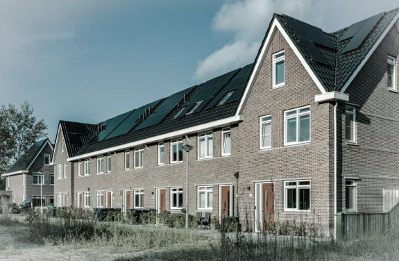 Case cu panouri fotovoltaice pe acoperis, simbolizand sustenabilitatea si energia verde.