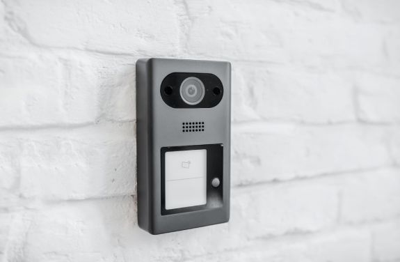 Interfon modern montat pe un perete din caramida alba, oferind un aspect elegant si functional.