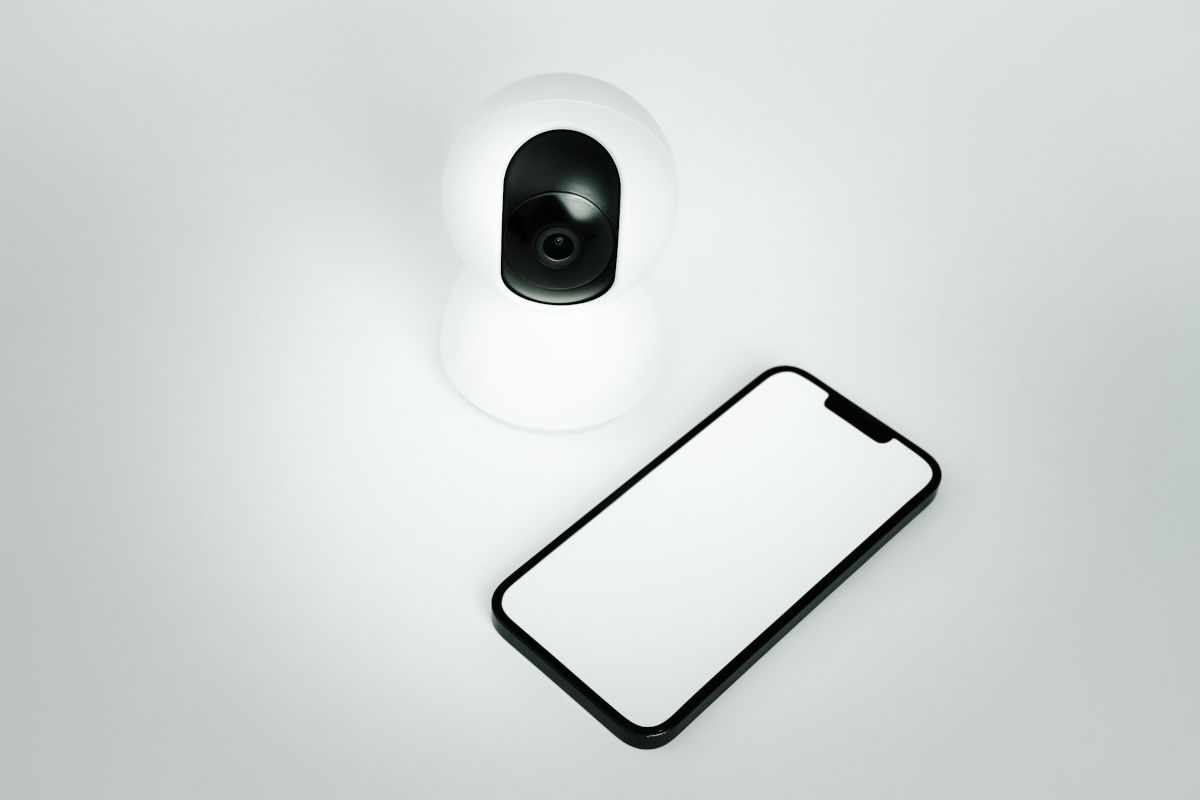 Redare 3D a unui smartphone si a unei camere IP wireless de securitate pe fundal alb, simbolizand protectia locuintei.