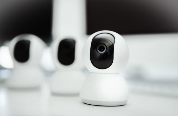 Trei camere de supraveghere asezate pe o masa, pregatite pentru instalare.