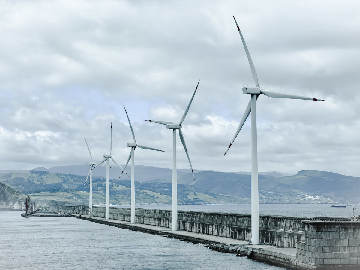 Un grup de turbine eoliene pe apa, simbolizand productia de energie verde si sustenabilitate.