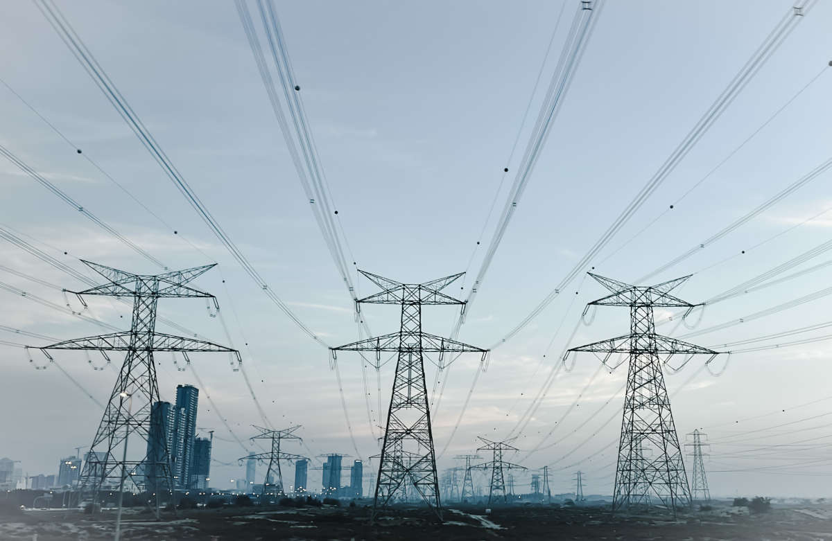 Stalpi de electricitate si turnuri in mijlocul unui camp, evidențiind infrastructura energetica moderna.
