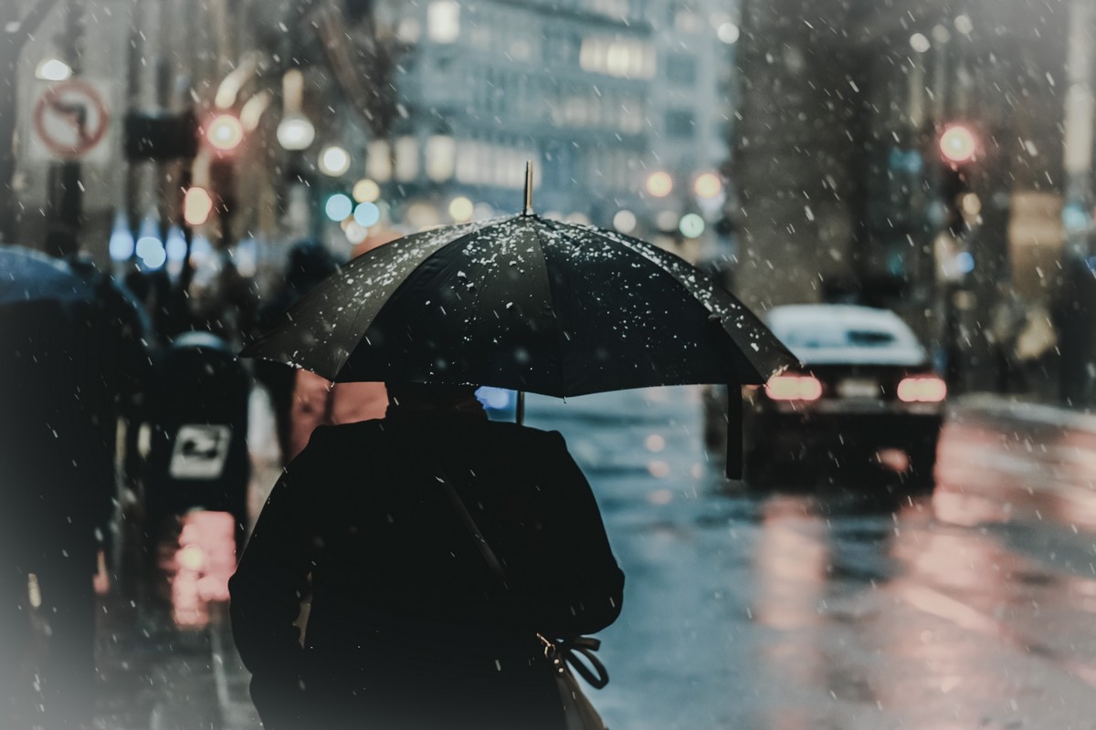 O persoana merge pe strada cu o umbrela, protejandu-se de ploaia inghetata si conditiile meteo extreme.
