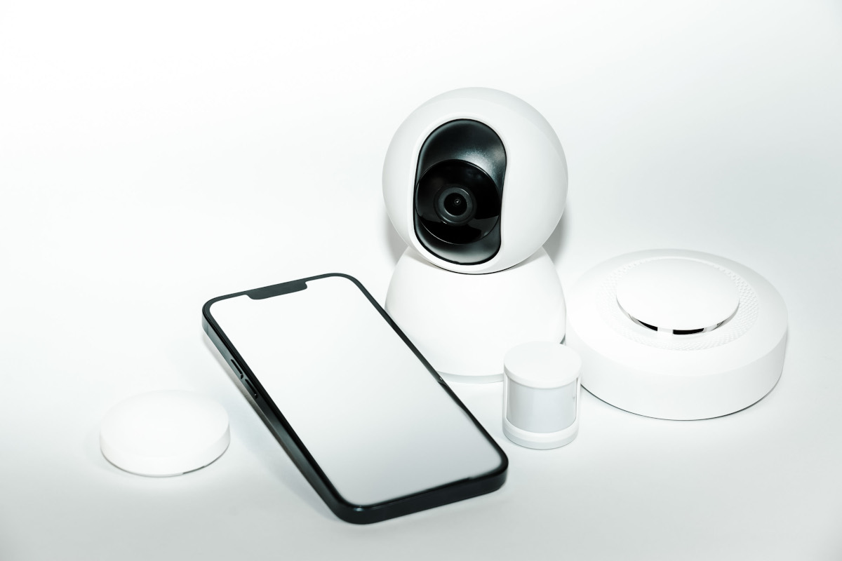 Camera de securitate inteligenta, telefon mobil si detector de fum adresabil pe fundal alb.