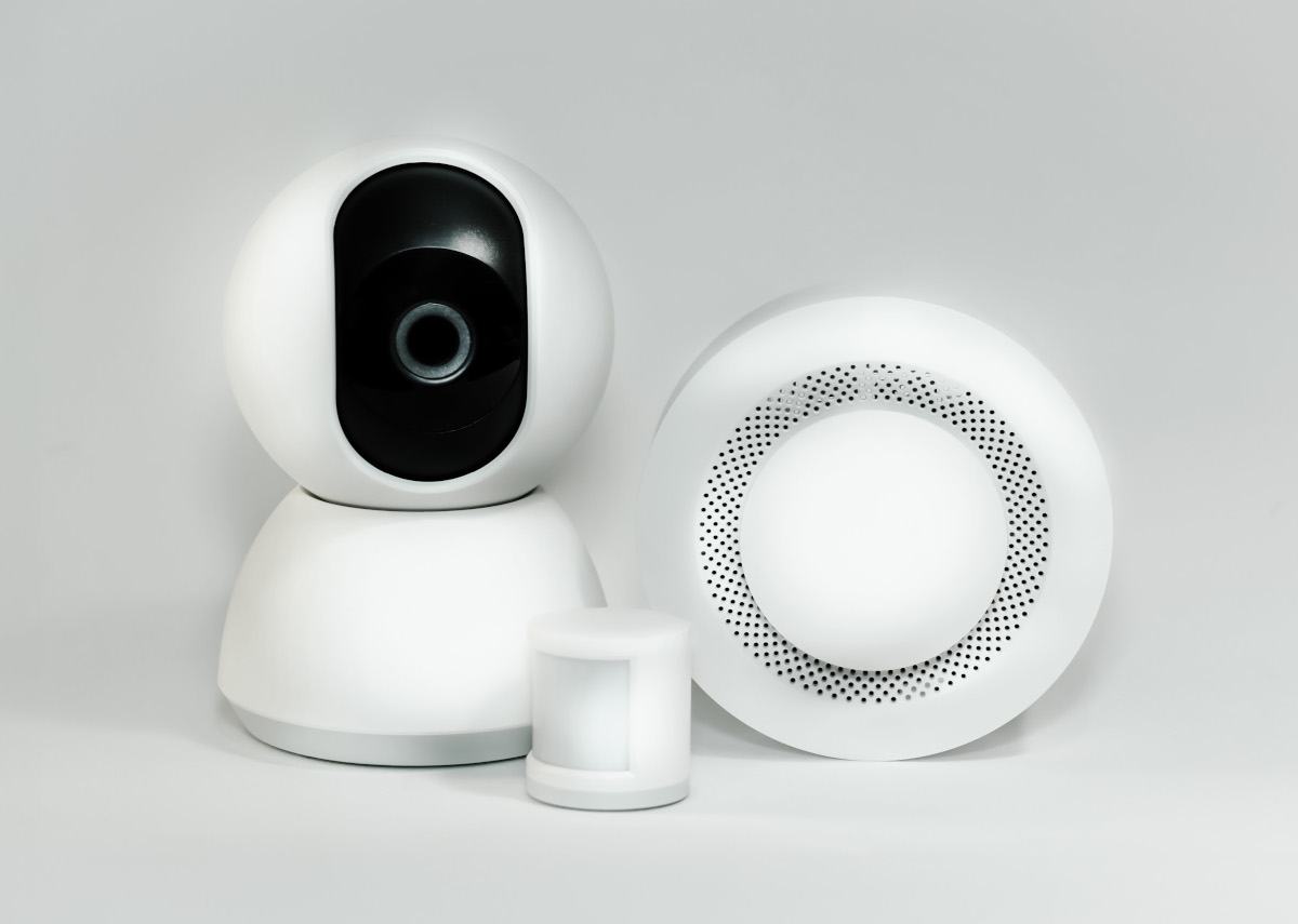 Camera de securitate alba si detector fum, combinatie perfecta pentru un sistem smart home sigur si confortabil.