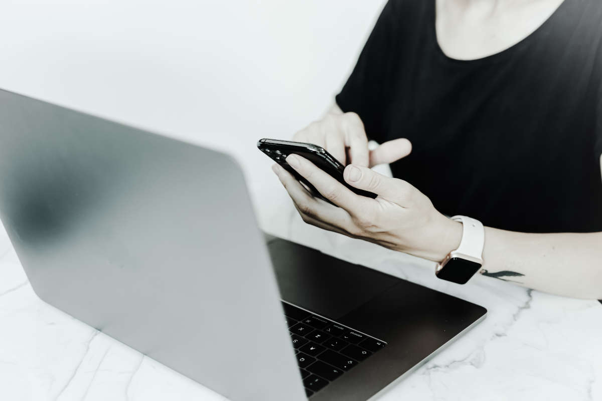 O persoana interactioneaza cu un smartphone si un laptop, in timp ce se bucura de o sonerie video.