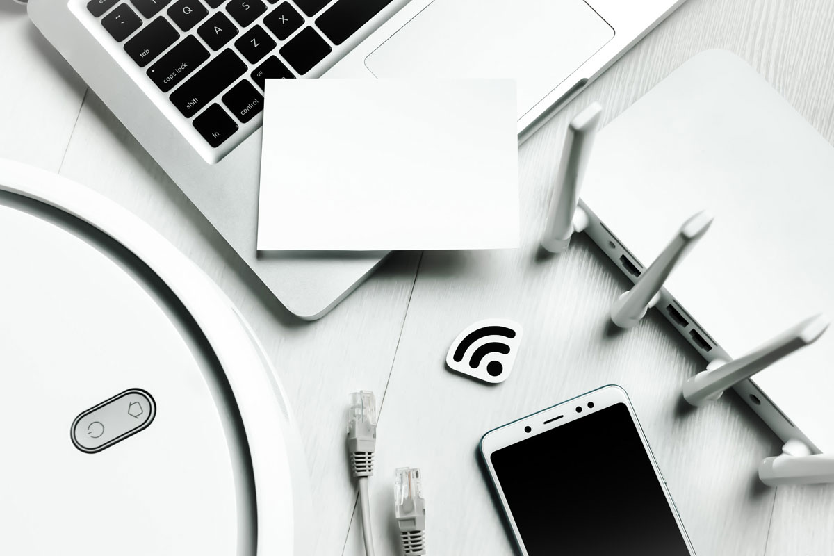 O masa cu un laptop, un telefon si diverse dispozitive electronice, gata pentru activitati digitale.