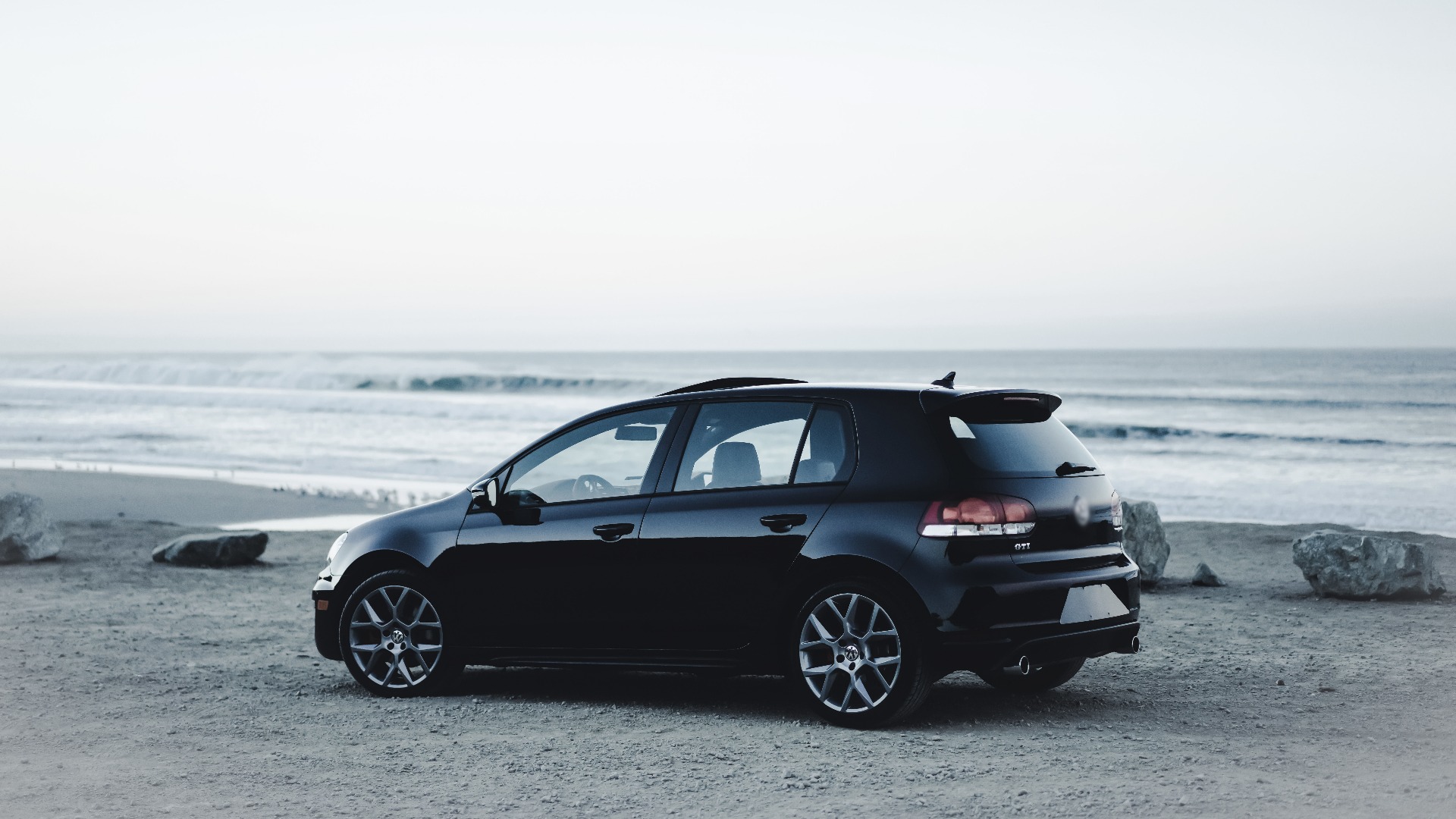 O masina neagra dotata cu camera auto de supraveghere interior stationata pe plaja, langa ocean.