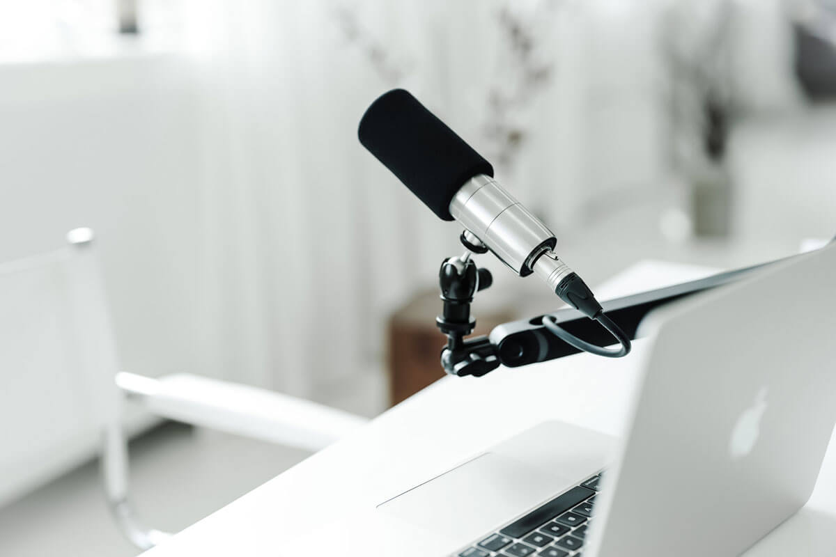 Un microfon cu cablu audio si un laptop asezate pe un birou, pregatite pentru o sesiune de inregistrare sau videoconferinta.