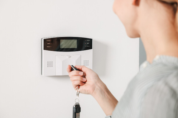 O femeie cu o cheie in mana, pregatita sa activeze sistemul de alarma al casei cu senzori de miscare.