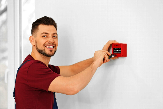 Un barbat instaleaza o alarma, parte dintr-un sistem antiincendiu pentru siguranta.