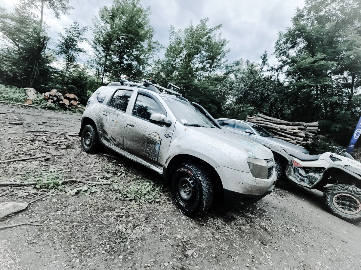 Un SUV alb parcat pe marginea unui drum de pamant, inconjurat de natura si liniste la Overload Scars