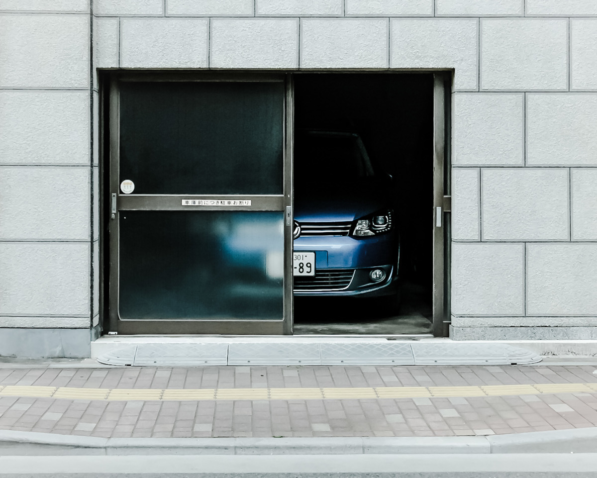 O masina albastra este parcata in apropierea unei usi de garaj dotata cu encoder dublu.